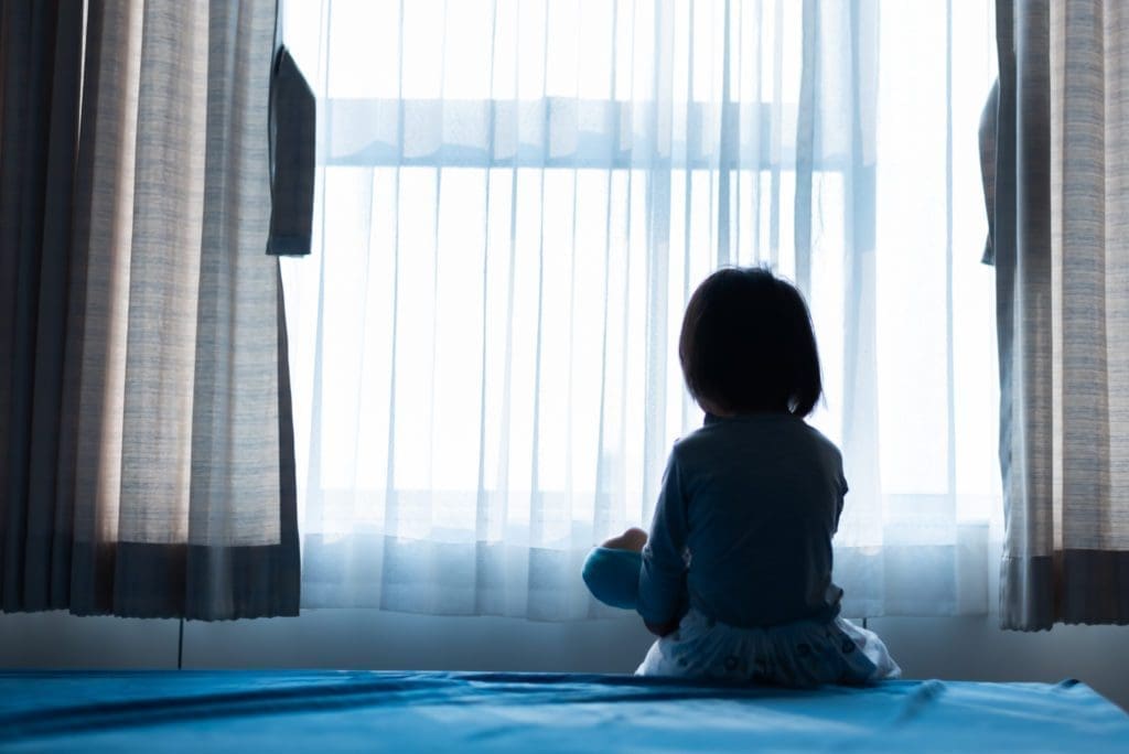 A child sits in a room alone.