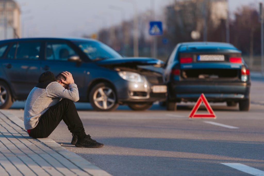 A man sits outside a car accident