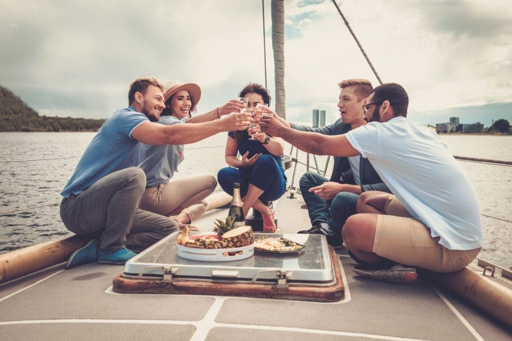 A group of friends drinks alcohol and operates a motoboat.