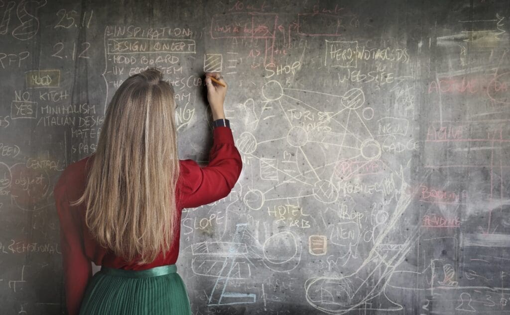 A teacher writes on a chalk board