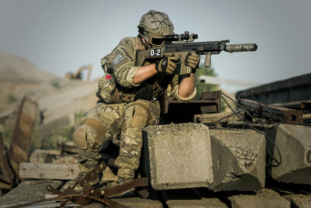 A soldier holders a weapon that has a firearm silencer attached to it.